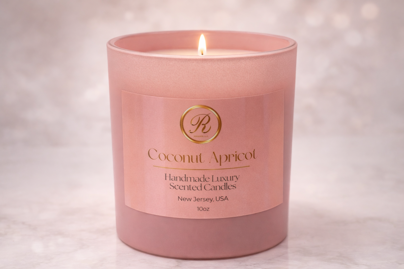 A handmade luxury Coconut Apricot candle in a frosted blush glass jar, softly glowing on a white stone countertop in a modern kitchen, illuminated by warm candlelight for an elegant, cozy ambiance.